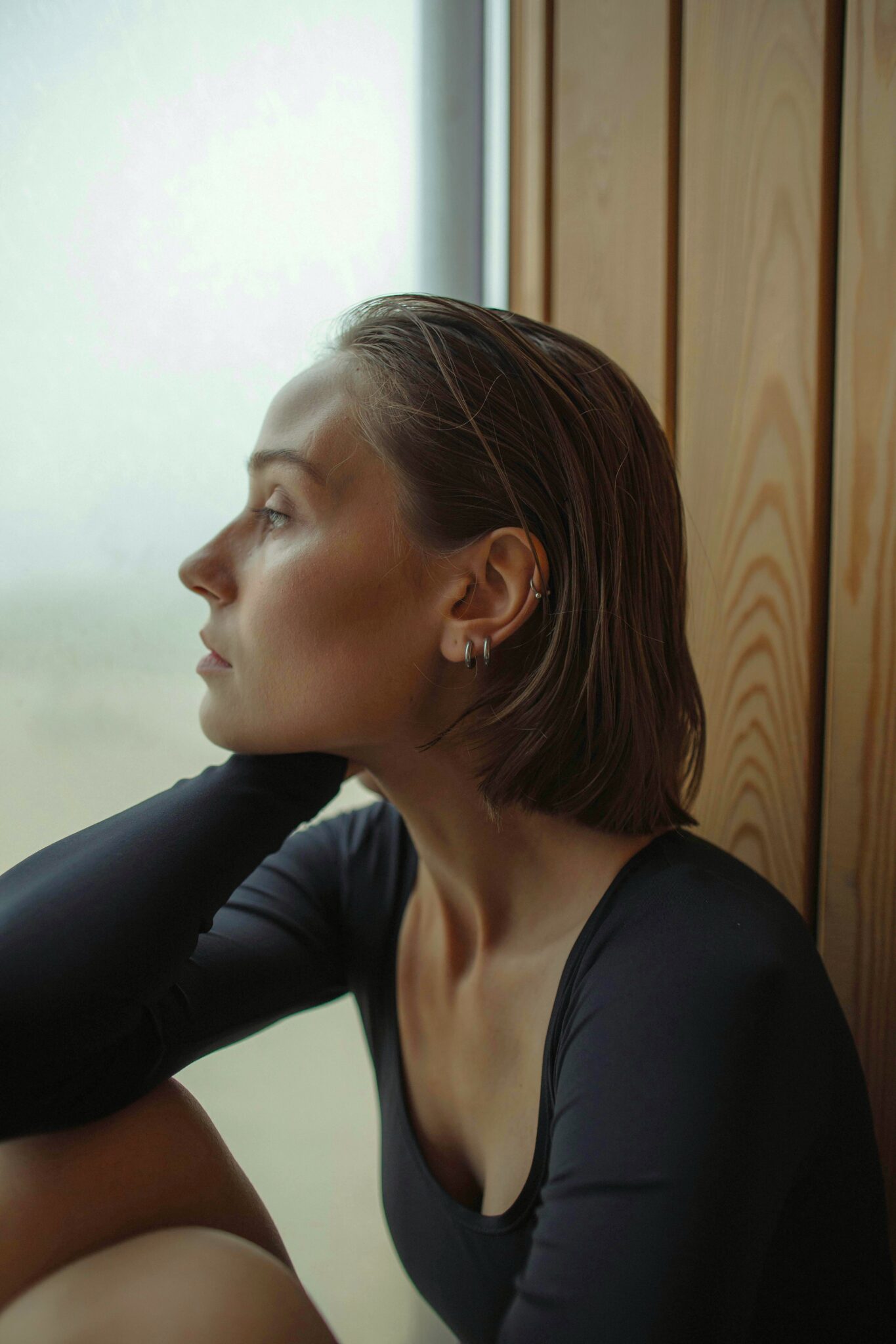 Femme pensive, stressée, regardant par la fenêtre, exprimant une douleur physique, une fatigue émotionnelle ou un état d’anxiété, avant une séance de magnétisme et de soins énergétiques réalisée par Anthony Malaquin, Thérapeute magnétiseur à Hulluch (proche de Lens, Arras, Liévin, Béthune, la Bassée, Lille) ou à distance
